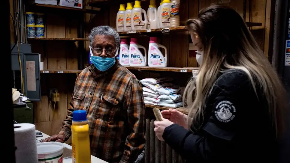 Fotografía que muestra a Ismael Taveras (i) mientras atiende a una clienta en el Graham Laundromat, el negocio familiar en el que trabaja. EFE/ Alba Vigaray/Archivo