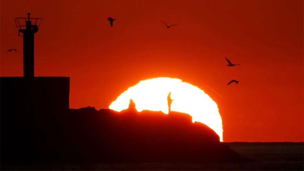 Dos pescadores faenan mientras el sol se pone en la punta del muelle del puerto de la localidad coruñesa de Portosín. EFE/ Lavandeira Jr/Archivo