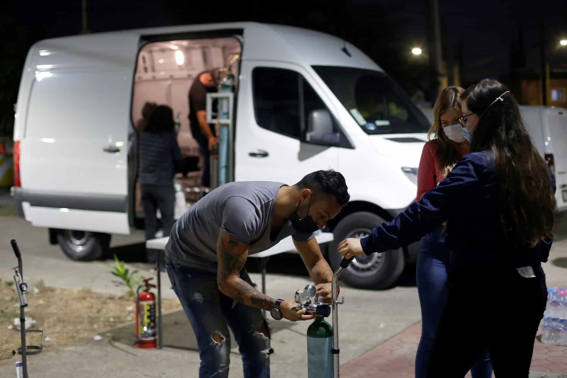 Integrantes de la brigada “Oxígeno en ruedas” llevan tanques de oxígeno a personas que lo necesitan. EFE/ Francisco Guasco