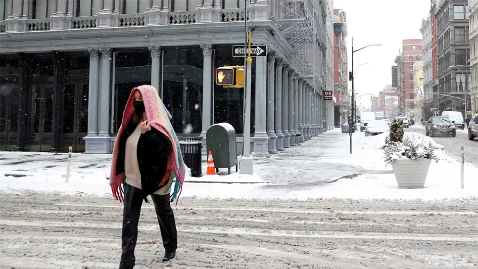 Una mujer viste una bufanda mientras cruza por la calle de SOHO en Nueva York. EFE/EPA/JASON SZENES