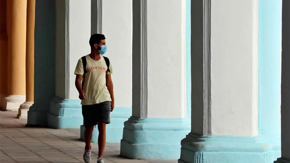 Un joven camina con mascarilla por unos portales en La Habana Vieja (Cuba). EFE/ Ernesto Mastrascusa/Archivo
