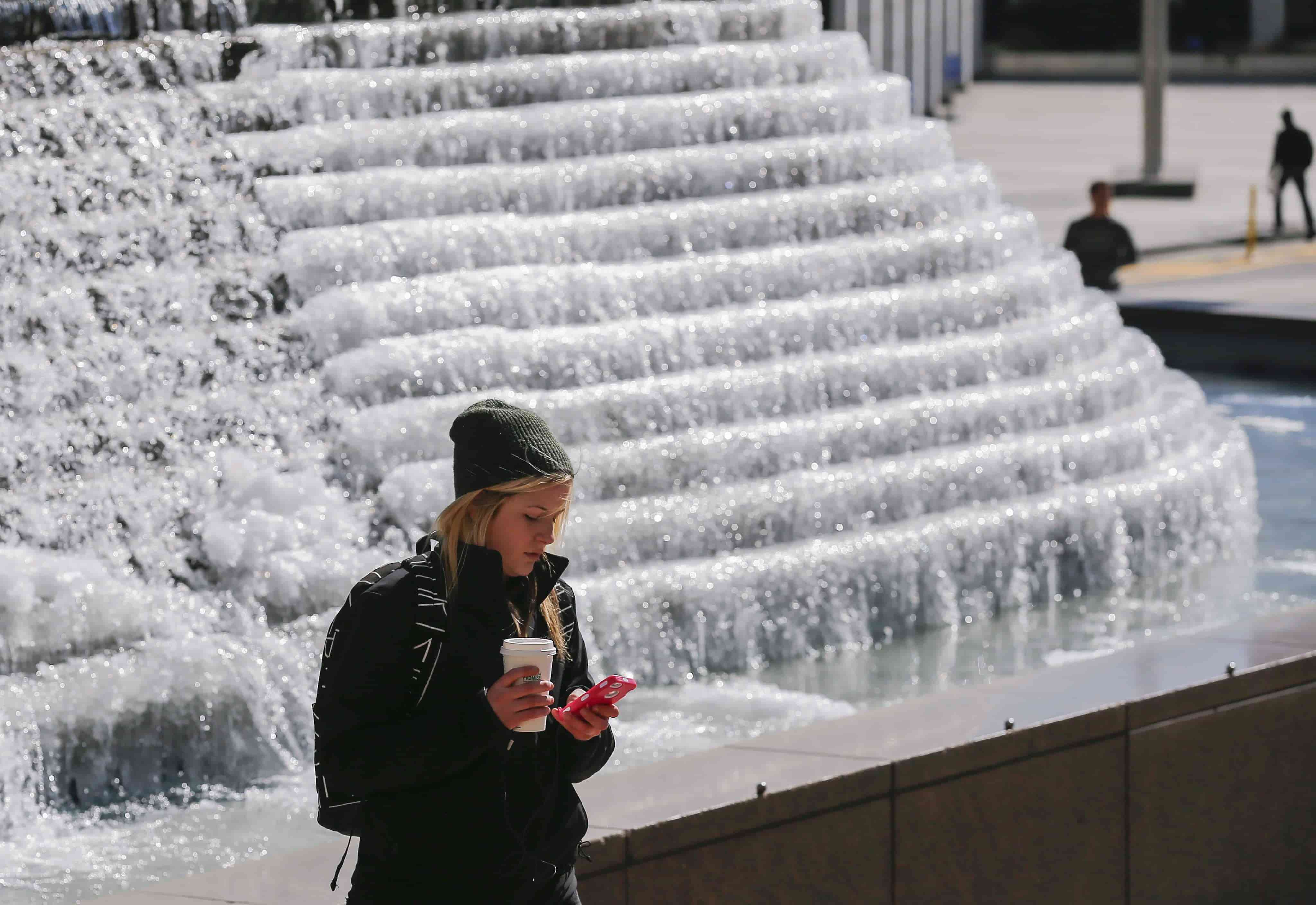 Imagen de archivo de una mujer observando su celular frente a una fuente congelada en el parque de Woodruff, en el centro de Atlanta, Georgia (EEUU). EFE/Erik S. Lesser.