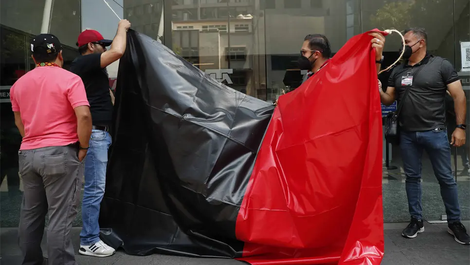 Trabajadores del Sindicato de Telefonistas de la República Mexicana (STRM) de Telmex, retiran las banderas rojinegras hoy al llegar un acuerdo para suspender la huelga en la Ciudad de México (México). EFE/ José Méndez.